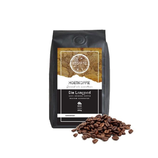 A pack of Die Langpad Moerkoffie coffee beans with a medium roast label, indicating a strong body and caramel flavors. The beans are displayed in front of the packaging.