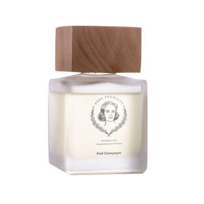 A clear glass fragrance diffuser bottle with a wooden top, labeled 'Anke Products Pink Champagne'.