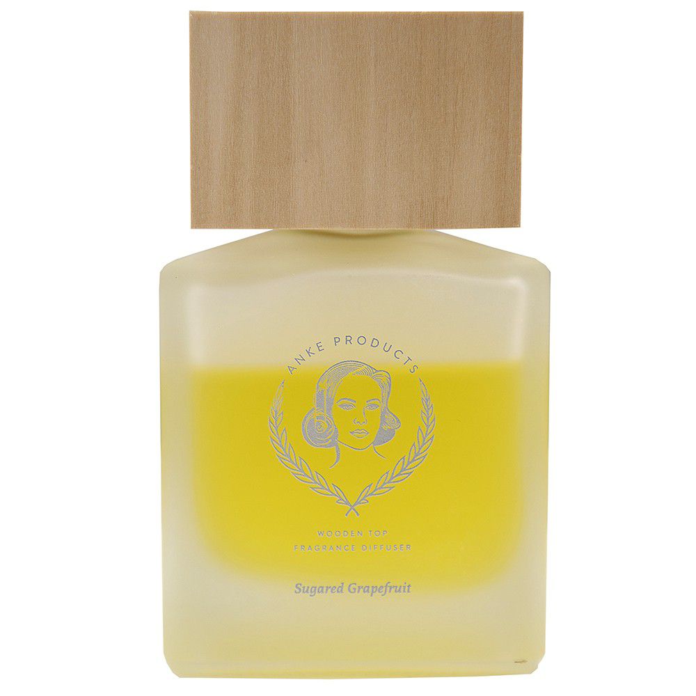 A clear glass fragrance diffuser bottle with a wooden lid, labeled 'Anke Products' and 'Sugared Grapefruit'.