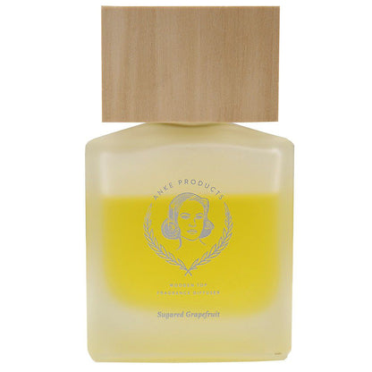 A clear glass fragrance diffuser bottle with a wooden lid, labeled 'Anke Products' and 'Sugared Grapefruit'.